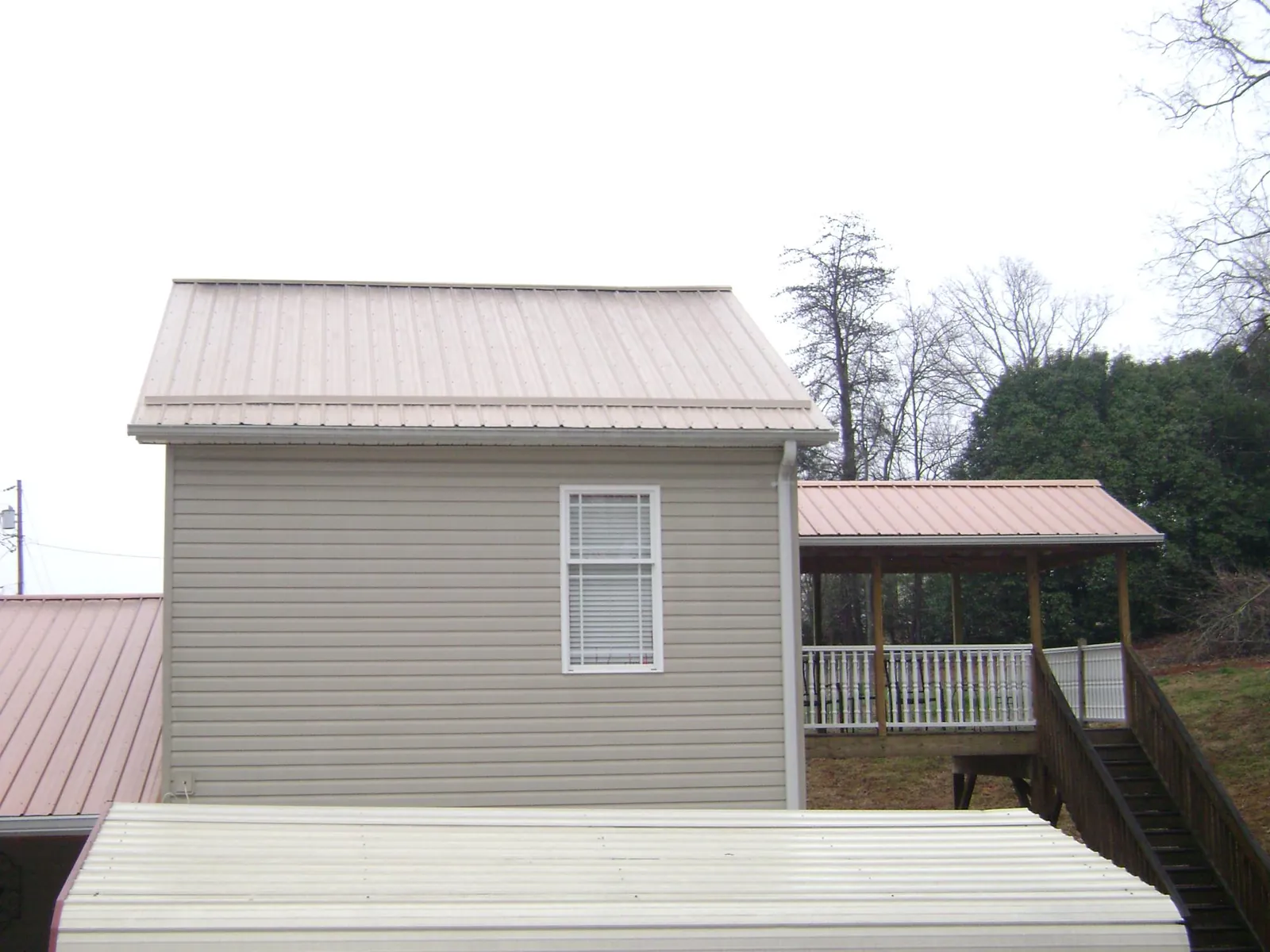 Tan metal roofs on a two story addition and attached porch, from a Roof Replacement job in Shields