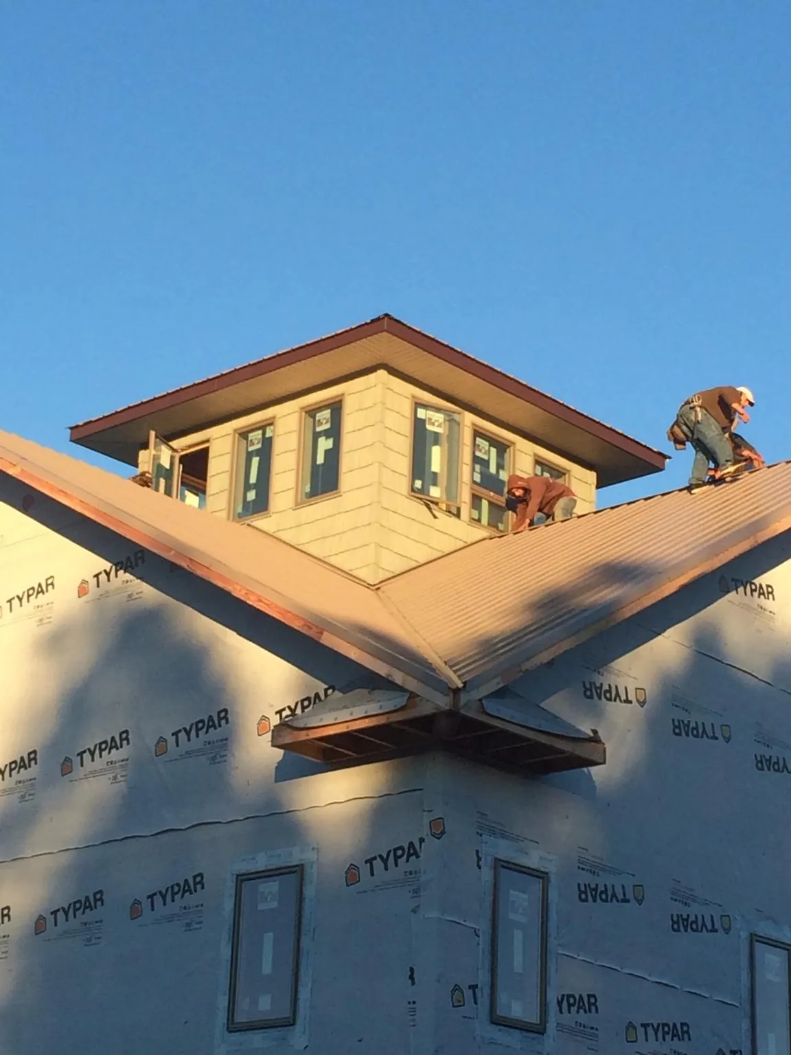 Roofers working around a rooftop cupola on a new metal roof at sunset — Roof Waterproofing in Shields by Roofing Brothers